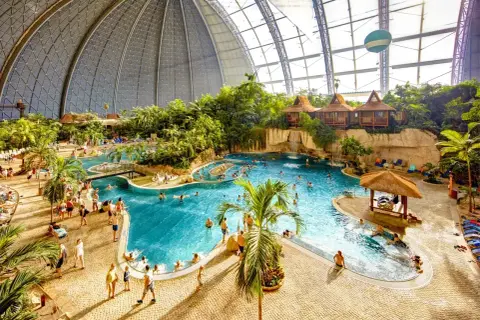 Wielki basen Tropical Island w Berlinie, z palmami, wodospadami i domkami na wodzie.