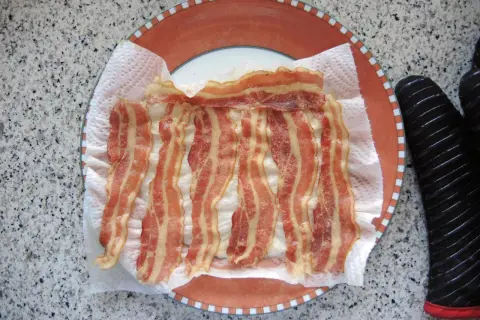 Fertig gegrillter Bacon auf Küchenpapier auf einem Teller. Schnell und einfach in der Mikrowelle zubereitet.