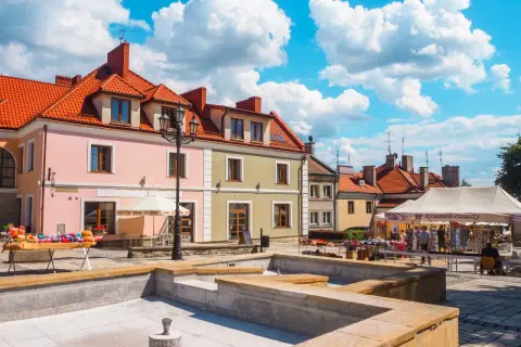 Sandomierz rynek tętni życiem. Kolorowe kamienice, stragany z pamiątkami i błękitne niebo tworzą malowniczy widok.
