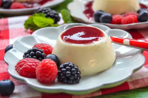 Cremige Panna Cotta mit Beeren und roter Soße, ein Genuss für Augen und Gaumen.