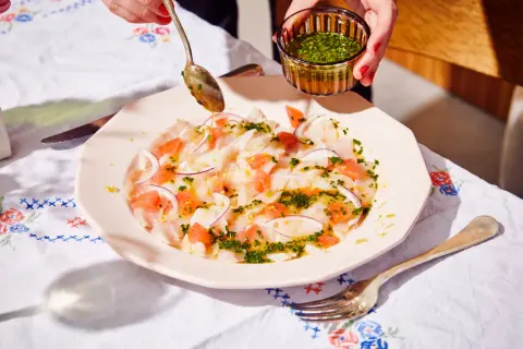 Préparation d'un carpaccio de bar frais avec pamplemousse, oignon rouge et une vinaigrette aux herbes.
