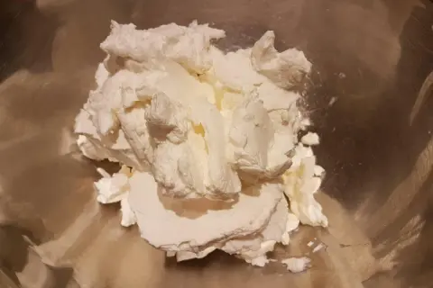 Krem z mascarpone w metalowej misce, gotowy do ubijania.