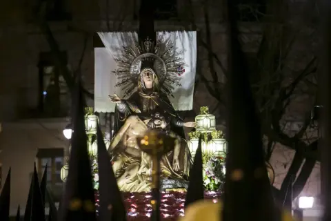 Procesión de Jueves Santo Zaragoza: imagen de la Virgen con el cuerpo de Cristo, rodeada de faroles y capirotes.