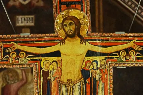Stary krzyż franciszkański z malowanymi postaciami Jezusa, aniołów i świętych.