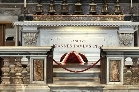 Grób Jana Pawła II w Watykanie. Marmurowa płyta z napisem "Sanctus Ioannes Paulus PP. II" i wieniec z czerwonych róż.