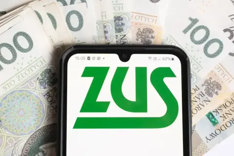 Telefon z logo ZUS na tle banknotów 100 zł. Czas na opłacenie składek ZUS.