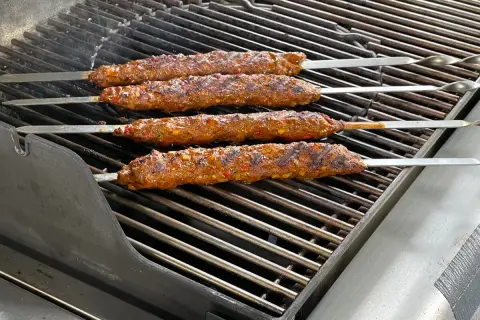 Vier saftige Adana Kebap Spieße brutzeln auf dem Grill. Das perfekte Adana Kebap Rezept für den Sommer.