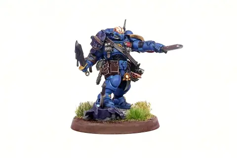 Błękitny Space Marine z mieczem i toporem, gotowy do walki. To zdjęcie na studia, ukazujące szczegóły figurki.