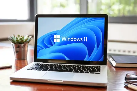 Laptop z logo Windows 11 na ekranie. Sprawdź, czy Twój sprzęt spełnia **windows 11 wymagania**, by cieszyć się nowym systemem.