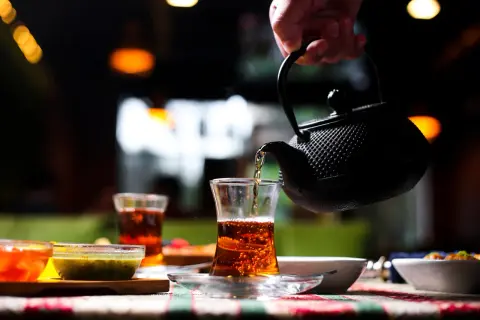 Une main verse du thé ceylan bienfait dans un verre. Ambiance chaleureuse et réconfortante.