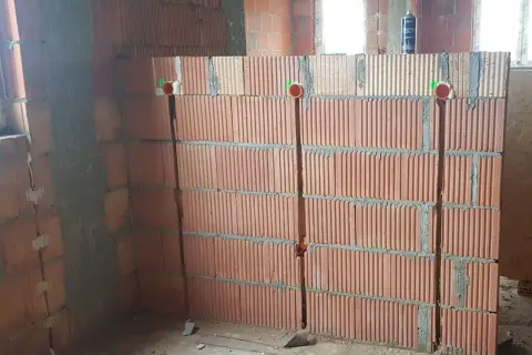 Bruzdowanie pod kable cena. Ściana z pustaków ceramicznych z wyciętymi bruzdami i puszkami instalacyjnymi.