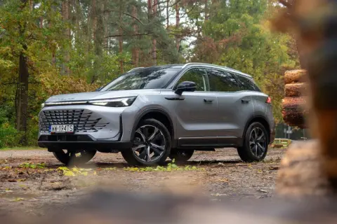 Srebrny SUV w lesie, gotowy na przygodę. Wiele pozytywnych baic 7 opinie potwierdza jego wszechstronność.
