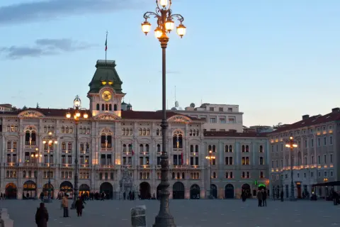 Piazza Unità d'Italia a Trieste, con i suoi palazzi illuminati e un cielo crepuscolare.