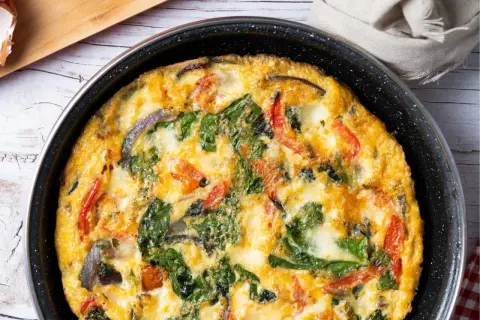 Pyszny omlet z cukinią, szpinakiem i pomidorami, zapieczony w patelni. Idealny na śniadanie lub lekki obiad.