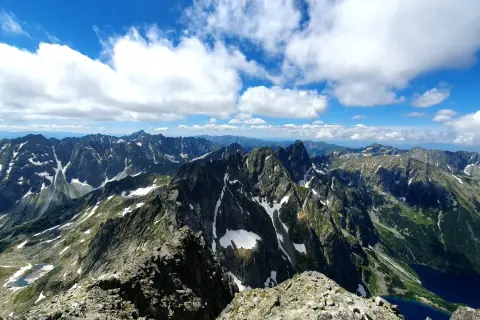Widok na pasmo górskie Rysy, gdzie szlak wije się wśród skalistych zboczy i resztek śniegu.