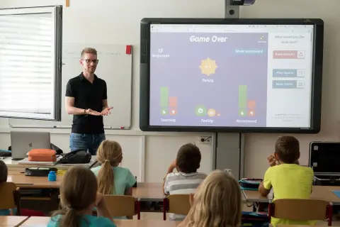Nauczyciel prowadzi zajęcia, które mogą być częścią przygotowania pedagogicznego dla psychologów. Uczniowie uczestniczą w interaktywnej lekcji.
