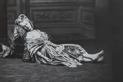 La comtesse de Castiglione, vêtue d'une robe somptueuse, repose, le visage serein, sur un sol en bois.