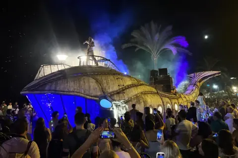 Una gran ballena mecánica ilumina la noche en una fiesta de los 90 en Zaragoza. El público, con móviles en mano, celebra el espectáculo.