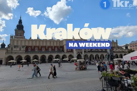 Tłum ludzi spaceruje po Rynku Głównym w Krakowie, ciesząc się piękną pogodą. Widać Sukiennice i wieżę Ratuszową.