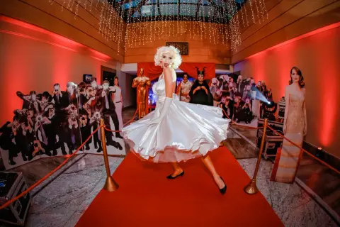 Kobieta w sukni Marilyn Monroe na czerwonym dywanie, otoczona wycinankami gwiazd i paparazzi. Prawdziwa styl hollywood impreza!
