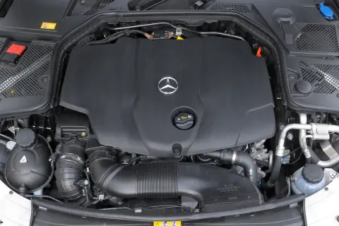 Silnik w Mercedesie C W205. Widoczna czarna osłona z logo producenta, przewody i elementy układu dolotowego.
