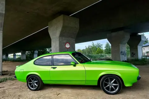Zielony Ford Capri z lat 70. pod betonowym wiaduktem.