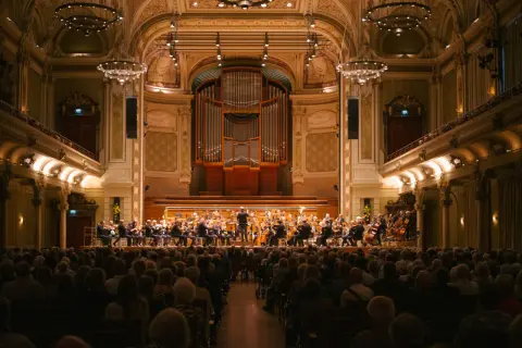 Ein Orchester spielt im prunkvollen Saal des Opernhauses Wuppertal vor einem begeisterten Publikum.