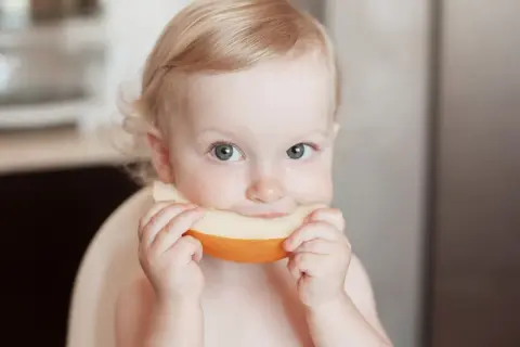 Ein süßes Baby genießt ein Stück Honigmelone.