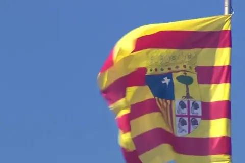 Bandera de San Jorge de Aragón ondeando con orgullo contra el cielo azul.