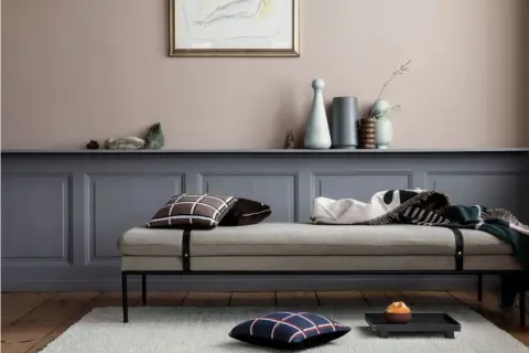 Ein Tagesbett mit Kissen und Decken vor einer Wand in einem sanften Rosaton. Welche Farbe wirkt beruhigend? Dieses Rosé schafft eine friedliche Atmosphäre.