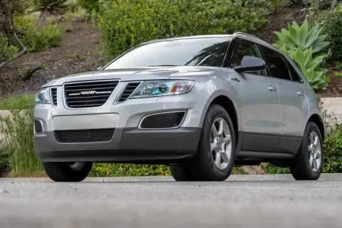 Silver Saab 9-4X SUV parkerad utomhus, med grönska i bakgrunden.