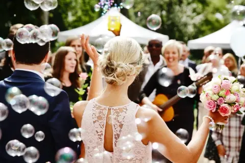 Une marraine, entourée de bulles, tient un bouquet de roses. Une femme joue de la guitare en arrière-plan.