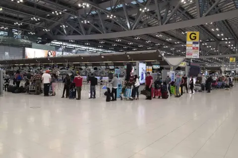 Menschen stehen in einer Schlange am Flughafen-Check-in. Gute **Kiwi com Erfahrungen** sind wichtig für entspanntes Reisen.