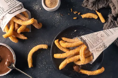 Frisch frittierte Churros, mit Zucker bestreut, serviert mit Schokoladensauce. Perfekt zum Churros selber machen!