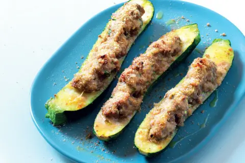 Zucchine tonde ripiene di carne, cotte al forno e servite su un piatto blu.