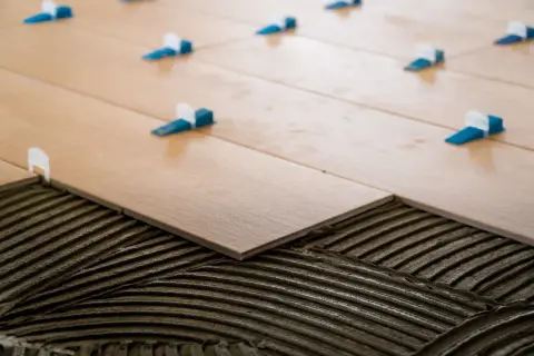 Pose d'un carrelage 60x120 pose décalée, avec des croisillons bleus et blancs assurant un espacement parfait pour un rendu impeccable.