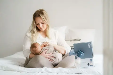 En mamma ammar sitt lilla barn. Bredvid dem står en bröstpump och dess förpackning.