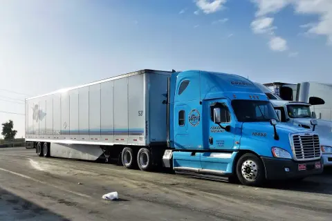 Błękitna ciężarówka Gordon Trucking z naczepą, gotowa do podróży door to door.
