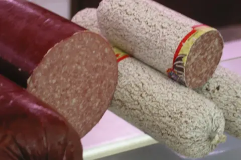 Kawałek ciemnej i jasnej salami, z czego jest salami, widać przekrój.