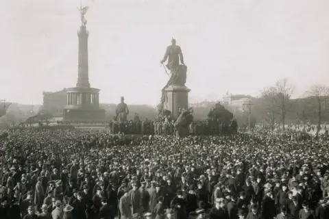 Menschenmenge vor dem Siegessäule-Denkmal in Berlin, ein Symbol der revolutionären Stimmung der Revolution 1918.