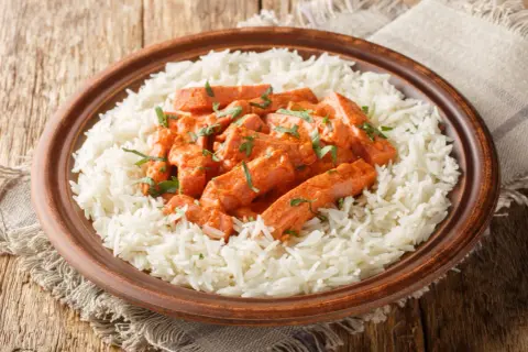 En tallrik med fluffigt ris och krämig korv stroganoff, toppad med färska örter. Perfekt för godaste korv stroganoff receptet.