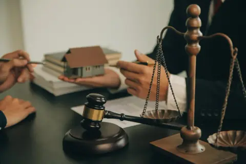 Sąd rozstrzyga sprawę o dziedziczenie ustawowe. Młotek sędziowski, waga sprawiedliwości i makieta domu symbolizują proces prawny.