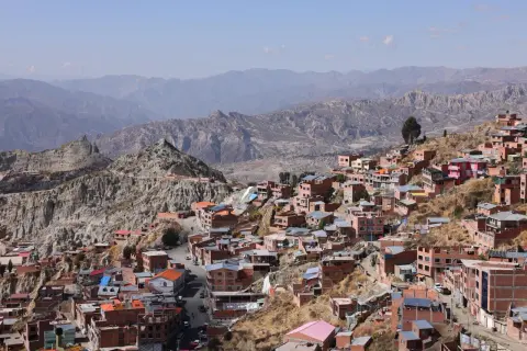 Färgglada hus klättrar uppför bergssluttningar i La Paz, bolivias huvudstad, med dramatiska berg i bakgrunden.