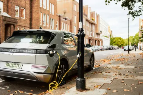 Coches eléctricos noticias: un Hyundai Ioniq 5 cargando en una calle de Londres, con edificios de ladrillo y hojas caídas.