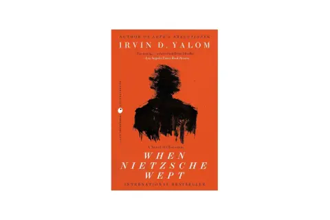 Okładka książki "Gdy Nietzsche płakał" Irvina D. Yalom z czarną sylwetką na pomarańczowym tle.