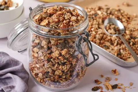 Ein Glas voller knusprigem, selbstgemachtem Granola ohne Zucker, mit Nüssen und Kernen. Perfekt für ein gesundes Frühstück.
