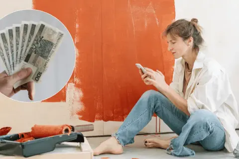 Kobieta planuje remont mieszkania, przeglądając telefon. W tle widać farbę i wałek, a w rogu zdjęcie pieniędzy, sugerujące dotację na remont mieszkania.