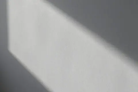 Światło podkreśla nierówności na elewacji, tworząc cień o geometrycznym kształcie.