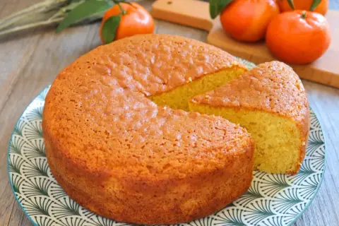 Bizcocho de mandarina esponjoso y dorado, con una porción cortada, listo para disfrutar.