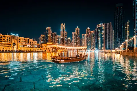 En båt glider fram på vattnet i Dubai i december, med upplysta skyskrapor som bakgrund.